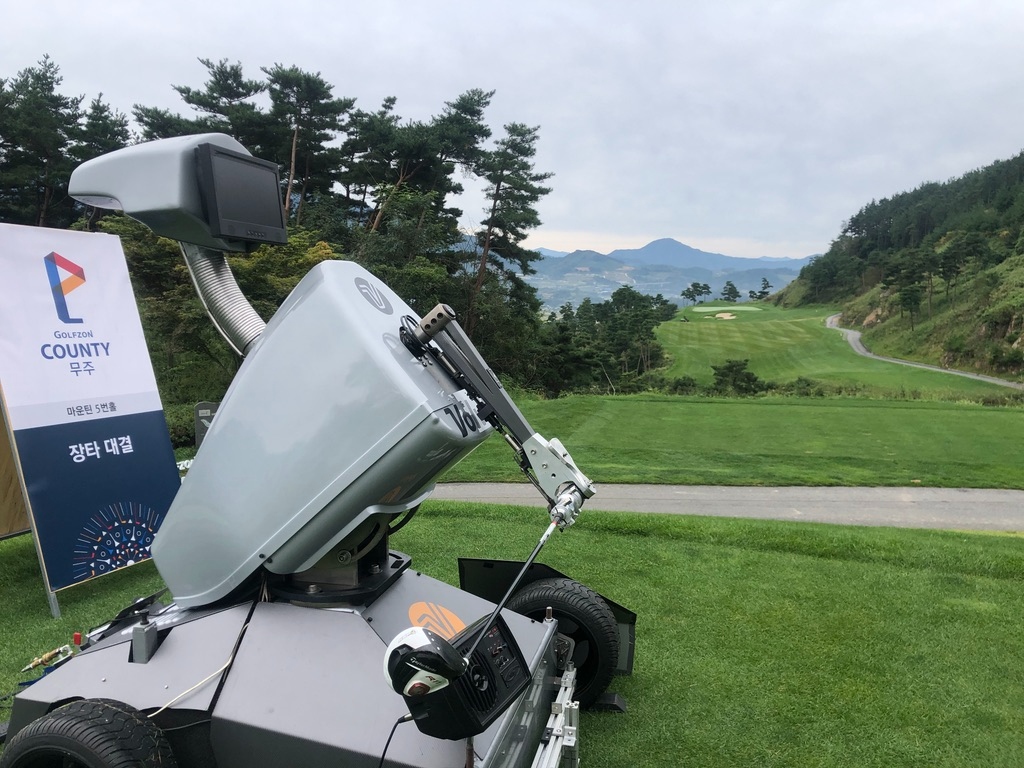 Rob-OT staged next to a branded charity event sign at a Korean mountain course