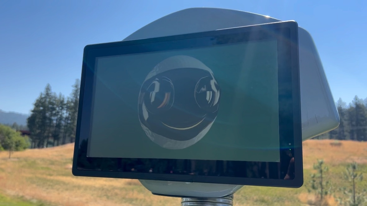 Rob-OT's on-board display showing his animated face outdoors against a blue sky