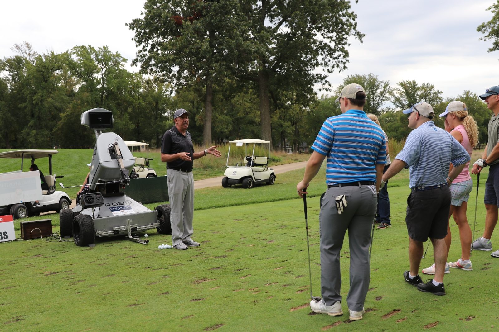 Gene Parente teaching a small group next to Rob-OT with clubs in hand at a corporate outing
